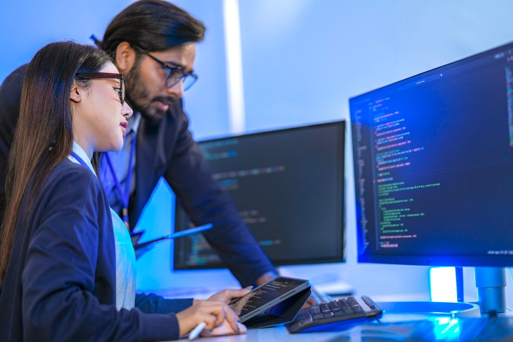 Senior engineer mentoring a junior female developer. Diverse tec - Bridge International College